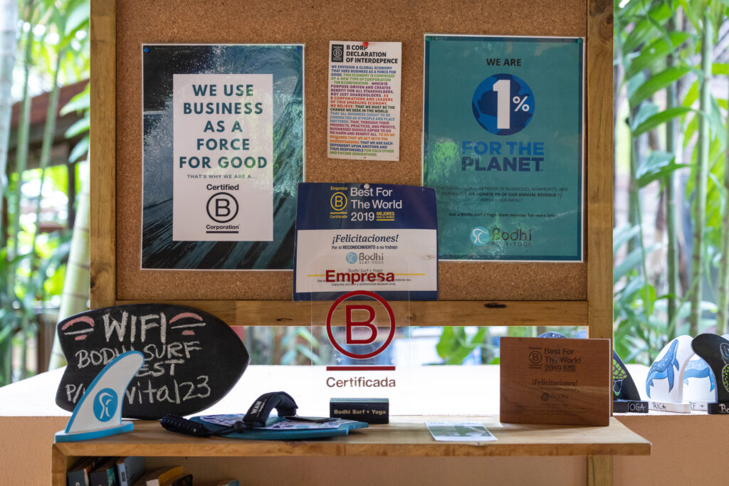 A table and cork board displaying B Corp award plaques and certificates,